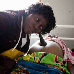 Malawian midwife using a foetal pinnard to listen to a baby's heartbeat in the womb